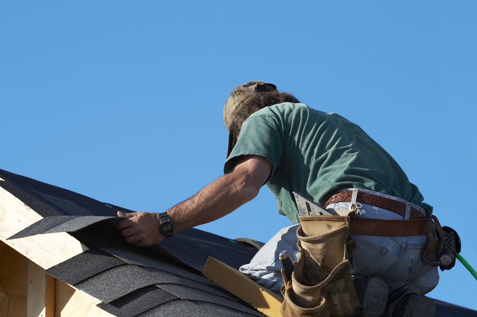 Roofer fastening shingles on a pitched roof
